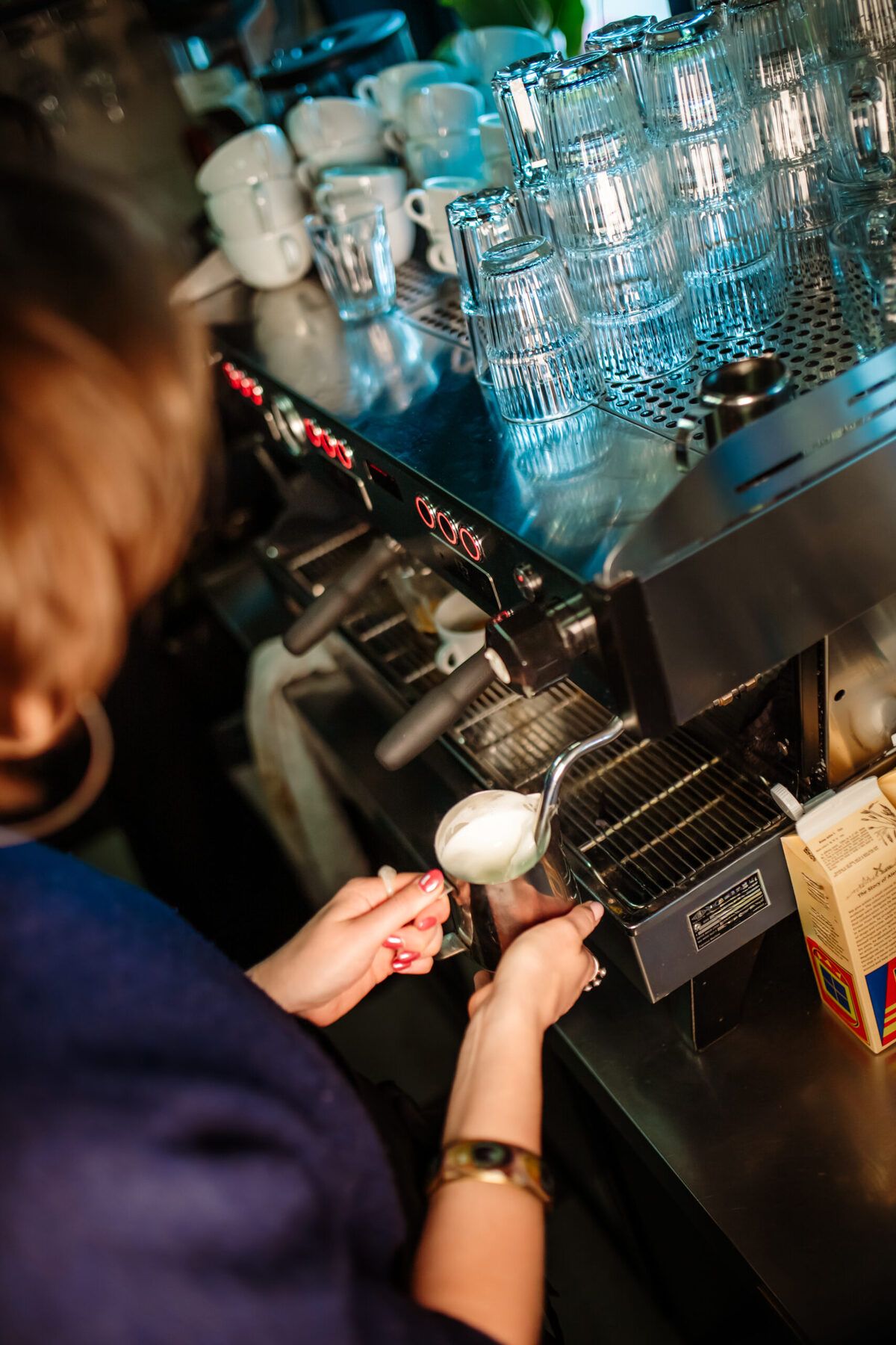 Een barista schenkt melk in een cappuccino